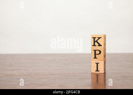 KPI letters written in black letters on a wooden block. Key performance indicator. Written on three blocks stacked on a wooden table.  Copy space on t Stock Photo