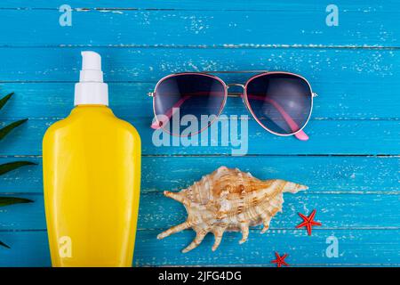 Flat lay composition with sunscreen and seashells on a blue wooden background. Stock Photo