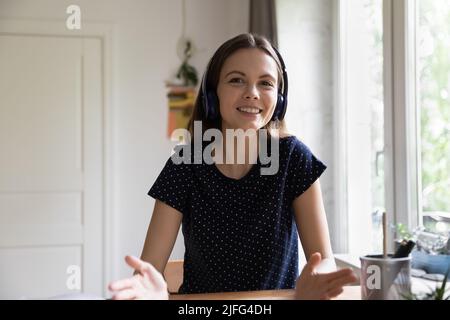 Happy young teacher woman in wireless headphones giving online lesson Stock Photo