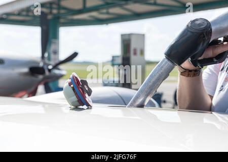 A close-up view of the aircraft's fuel tank, fuel is being filled into the tank. Fuel nozzle filling up aircraft, refueling jet fuel in an aircraft wi Stock Photo