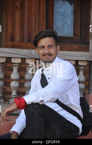 A happy young guy looking at camera while sitting on temple stairs Stock Photo
