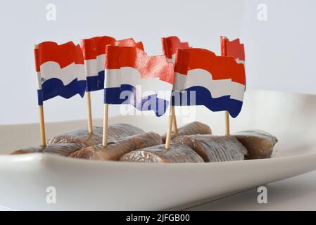 Den Helder, the Netherlands. June 2022. Fresh herring with onions and Dutch flags on a white background. High quality photo. Close up. Selective focus Stock Photo
