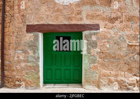 Stone facade with small old wooden door painted green at little town of Orbaneja del Castillo, Burgos, Spain, Europe Stock Photo