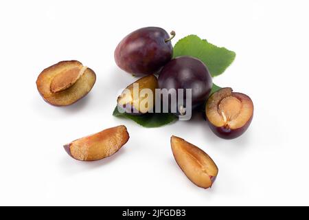 Tasty plums. Fresh plum fruits isolated on bright background, sliced and whole. Close up view. Stock Photo