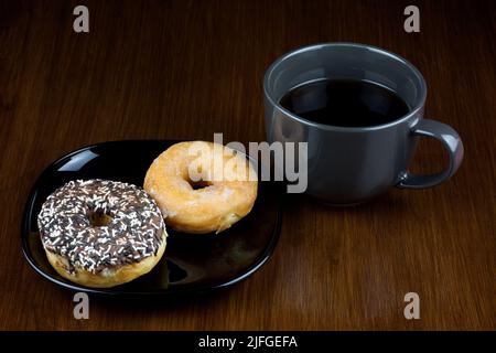 Cup of coffee and donuts on an old polished wooden table surface Stock Photo