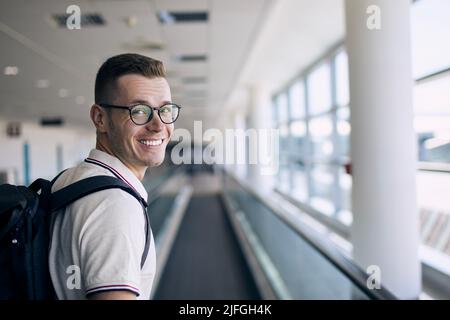 Portrait of smiling traveler at airport. Happy man looking at camera before his travel by airplane. Stock Photo