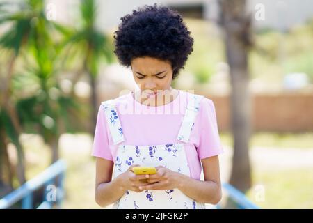 Focused black woman surfing smartphone on street Stock Photo