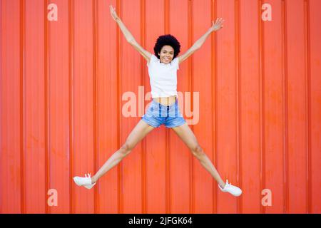 Happy black woman jumping on street Stock Photo