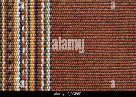 Brown textile background with copy space. Plain weave fabric with vertical stripes of white, yellow, green and black colors. Colorful woven fabric. Stock Photo