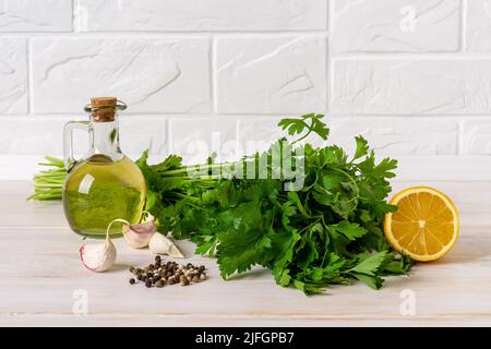 Green sauce ingredients. Salsa verde from fresh parsley, garlic cloves, olive oil and lemon juice. Homemade chimichurri dipping sauce recipe. Stock Photo