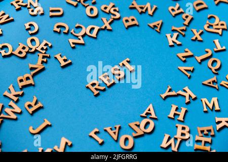 Word REST made out of wooden letters on bright blue background. Motivational Words Quotes Concept. Inspirational phrase Stock Photo