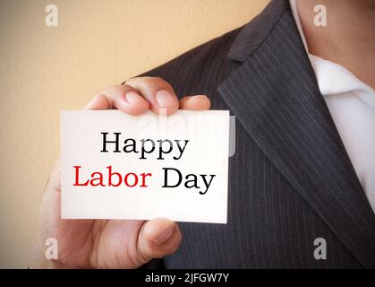 Close up a man wearing a suit showing a signboard with the text happy labor day written in it Stock Photo