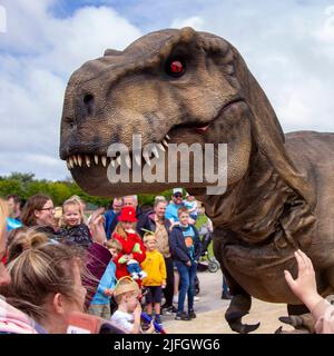 Dino Jurassic Live in Southport, Merseyside.  UK Entertainment, Jurassic Live- Meet the scarily realistic T-Rex Dinosaurs show event roarsome adventure in Victoria Park Far Away Land family festival.  Jurassic World Live is a live show produced by Feld Entertainment and NBC Universal based on the Jurassic World franchise.  Families with children flocked to Victoria Park for a 'Far Away Land' to see animatronic giant walking dinosaurs a pre-historic weekend experience. Stock Photo