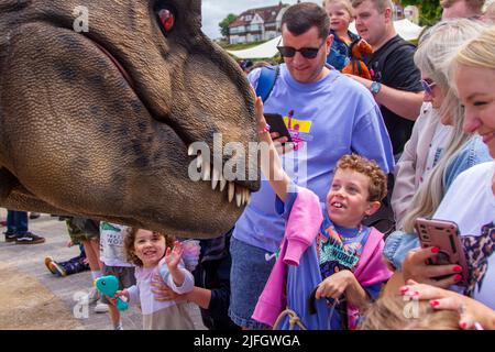 Dino Jurassic Live in Southport, Merseyside.  UK Entertainment, Jurassic Live- Meet the scarily realistic T-Rex Dinosaurs show event roarsome adventure in Victoria Park Far Away Land family festival.  Jurassic World Live is a live show produced by Feld Entertainment and NBC Universal based on the Jurassic World franchise.  Families with children flocked to Victoria Park for a 'Far Away Land' to see animatronic giant walking dinosaurs a pre-historic weekend experience. Stock Photo