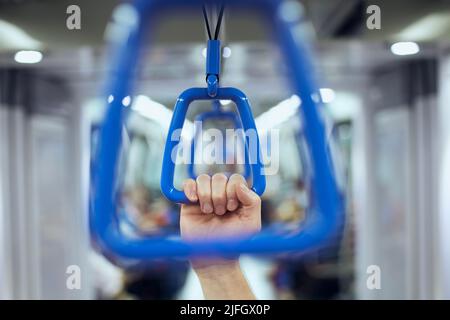 Hand holding handle in train of public transportation. Stock Photo