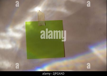 Green square piece of paper glued to the wall. Abstract light and shadow pattern on a gray plastered wall. Multitask background with copy space for te Stock Photo