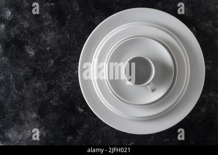 Many white empty ceramic plate and cup on black background, close up. View from above Stock Photo