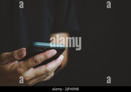 Person holding in hand mobile phone isolated on black background. Stock Photo