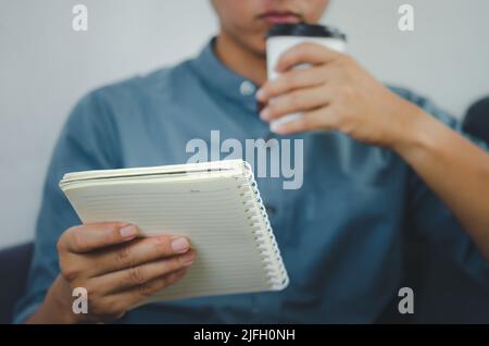 Person holding a note book and a paper coffee cup. Stock Photo