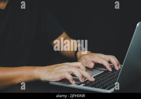 Person using in hand keyboard computer laptop on black background. Stock Photo