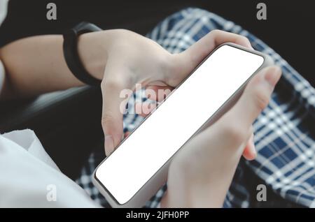 woman hand holding a mobile phone in the car cabin.Blank with white screen.Mock up smart phone interior car. Stock Photo