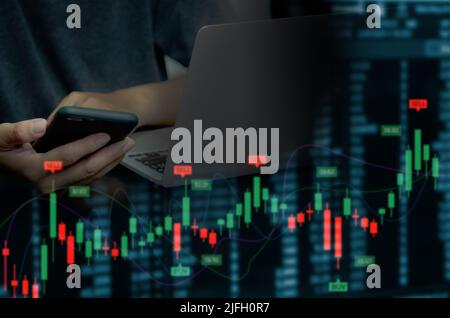 businessman using mobile phone and computer to find financial information. Candlesticks and graphs of the stock market economy.Virtual screen business Stock Photo
