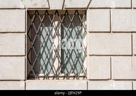 Closeup of a window with wrought iron security bars on a white marble wall. Trentino Alto Adige, Italy, Europe. Stock Photo