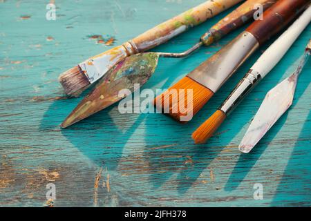 Artistic art supply utensils with paintbrushes on turquoise wooden background with copy space. Stock Photo