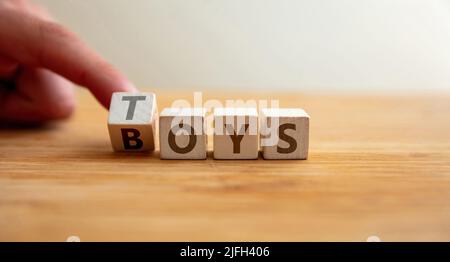Toys for boys concept. Finger flips letter at wooden cube changing the word toys to boys. Advertisement at store, message for creative construction an Stock Photo