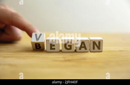 Began vegan lifestyle concept. Finger flips letter at wooden cube changing the word began to vegan. Message for starting healthy food, nutrition, diet Stock Photo
