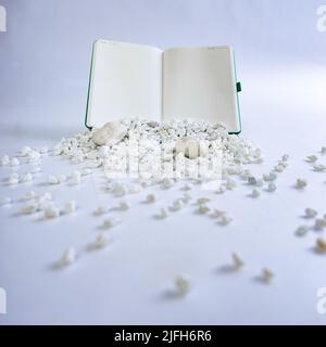 Notebook on white studio background. White rocks falling in front of it. Beautiful composition of notebook. High quality photo Stock Photo