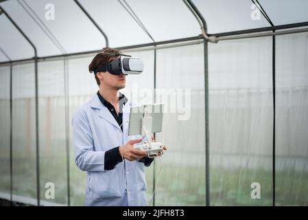Portrait of handsome agricultural researcher using VR glasses for research at plantation in industrial greenhouse Stock Photo