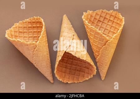 Set of three empty wafer ice cream cones on brown table. Top view Stock Photo