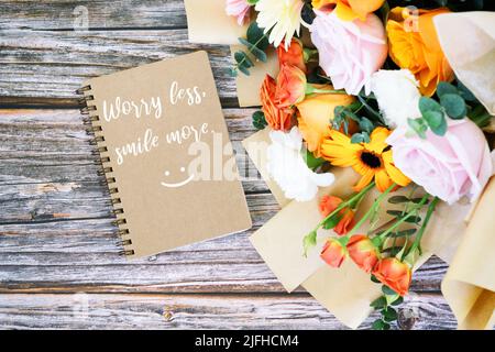 Note pad with text Worry less smile more with mixed flower bouquet Stock Photo