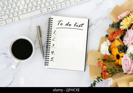 To do list text on note pad on top of office desk with bouquet of flower Stock Photo