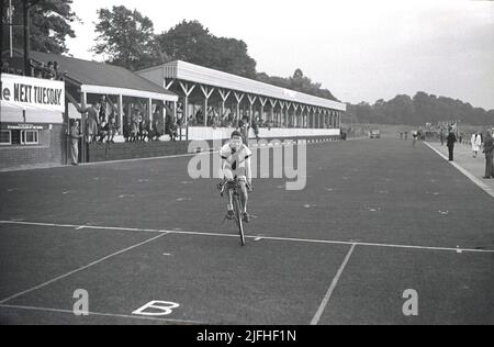 1937, historical, a racing cyclist crossing the line for a victory on the  motoring race circuit at Crystal Palace Park, South London, England, UK. The park was London’s first home of cycle racing in 1869, with its first dedicated cycle track opening in 1880. The motor racing circuit opened in the park in 1927, with motor cycle racing the first event. In 1936 the one mile circuit was extended to two miles and tarmac laid over its entire length and in 1937 the first London Grand Prix took place. Seen in the picture is the main grandstand of the motor racing circuit. Stock Photo