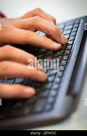 A man's hand typing on a keyboard Stock Photo