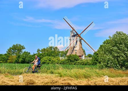 Tourist woman passing the Windmill in Oldsum  on June 29, 2022  in Wyk, Foehr Island, Germany.  © Peter Schatz / Alamy Stock Photos Stock Photo