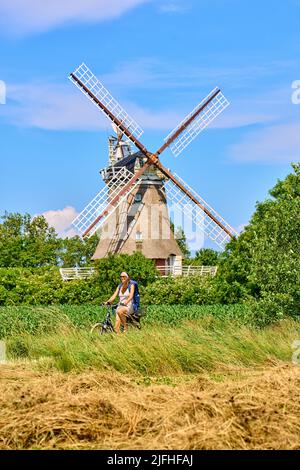 Tourist woman passing the Windmill in Oldsum  on June 29, 2022  in Wyk, Foehr Island, Germany.  © Peter Schatz / Alamy Stock Photos Stock Photo