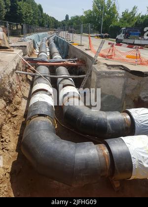 Reconstruction site of district heating system pipeline and replacement of old pipes with new ones. Laying heating pipes in a trench at construction s Stock Photo