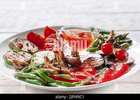 Grilled vegetables with red sauce on white plate Stock Photo