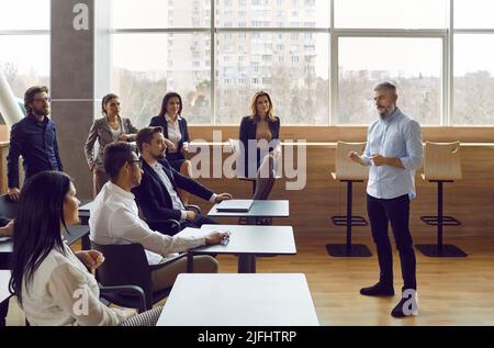Male coach present for diverse businesspeople in modern office Stock Photo