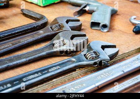 A collection of adjustable spanners on a wooden table top. Stock Photo