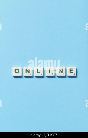 Online formed of scrabble blocks on blue background. Stock Photo