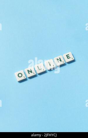 Online formed of scrabble blocks on blue background. Stock Photo
