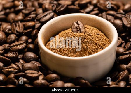Finely ground cinnamon in a white ceramic bowl on a background of coffee beans Stock Photo