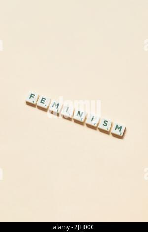 Feminism formed of scrabble blocks on beige background. Stock Photo