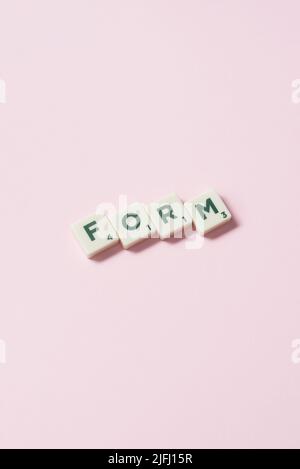 Form formed of scrabble tiles on pink background. Stock Photo