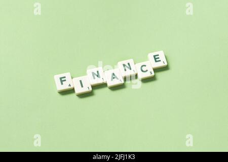 Finance formed of scrabble blocks on green background. Stock Photo