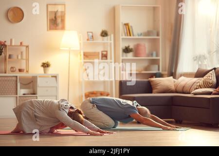 Active mature couple resting in childs pose while practicing yoga together at home Stock Photo
